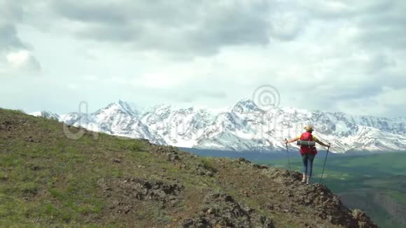 穿红色衬衫背着绿色背包的旅行者在山上花了不少钱看雪山视频的预览图