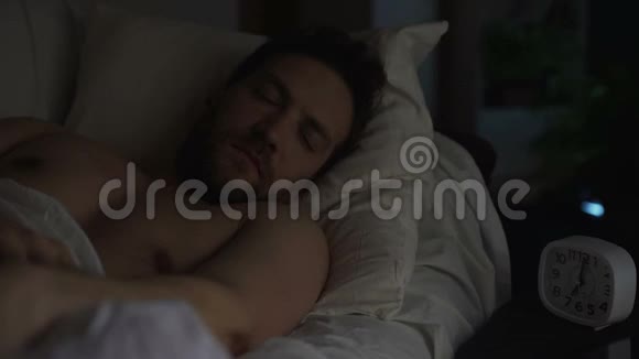 困乏的人关掉闹钟睡眠不足躺在床上的男人视频的预览图