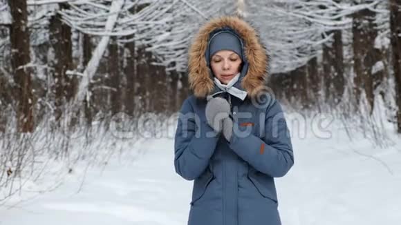 女人用呼吸在寒冷中温暖双手在冬天的森林里互相摩擦视频的预览图
