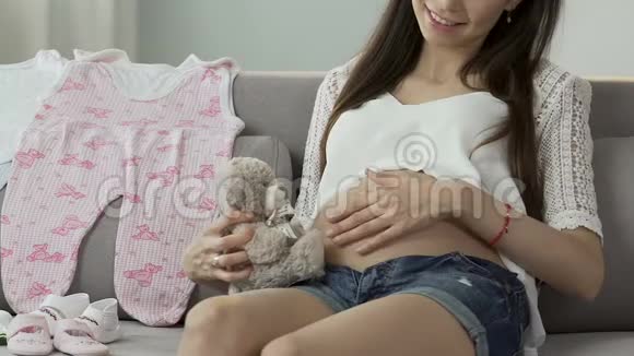 准妈妈抱着玩具熊在肚子旁边甜蜜的怀孕温柔视频的预览图