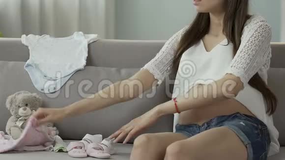 期待沙发上的女人拿着爬行动物看着它们快乐的怀孕视频的预览图