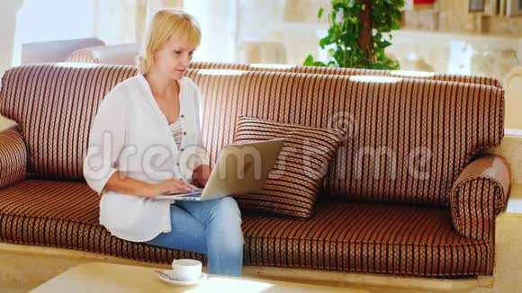 有魅力的女人在大厅里用笔记本电脑工作视频的预览图