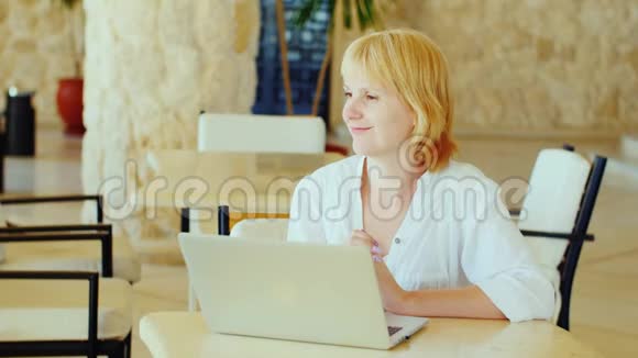 迷人的女游客在酒店大堂欣赏笔记本电脑视频的预览图