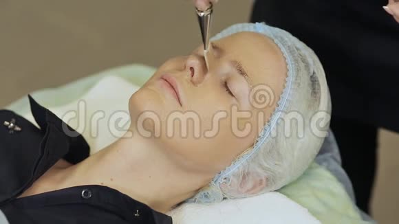 为在美容院戴化妆品面膜的年轻女性提供水疗疗法把巧克力面膜敷在女孩脸上视频的预览图