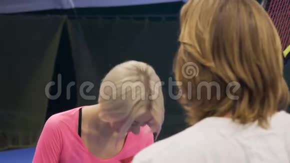 年轻漂亮的女人在网球场和男人说话视频的预览图