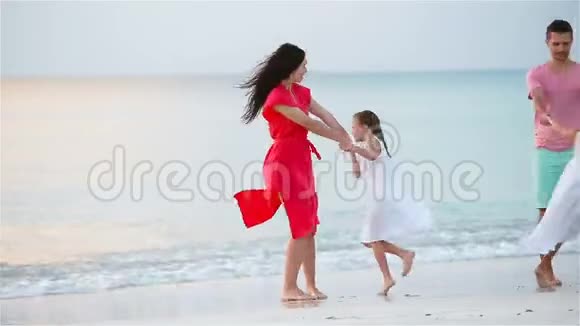 暑假期间在海滩上快乐的美丽家庭四口之家在海滩日落时玩得开心视频的预览图