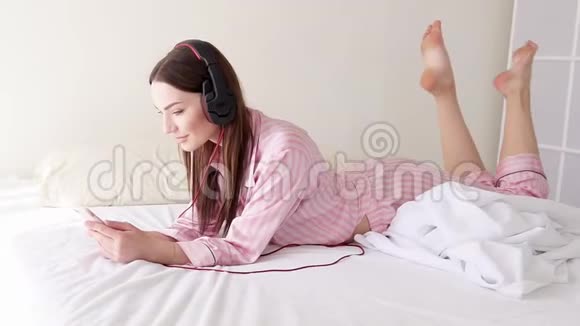 戴着大耳机躺着手机听音乐的女人视频的预览图