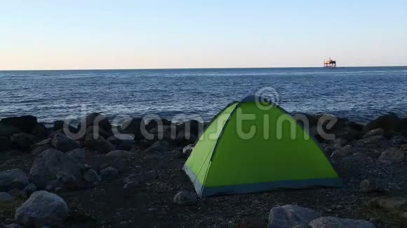 在落日的背景下在石质海滩上的旅游帐篷静态摄像机视频的预览图