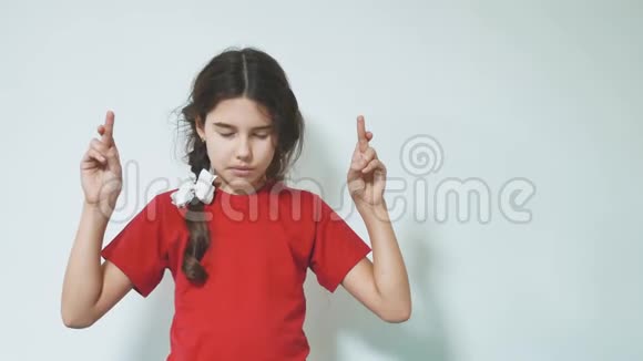 小女孩交叉手指来实现她的梦想手指交叉在白色背景上的女孩小女孩视频的预览图