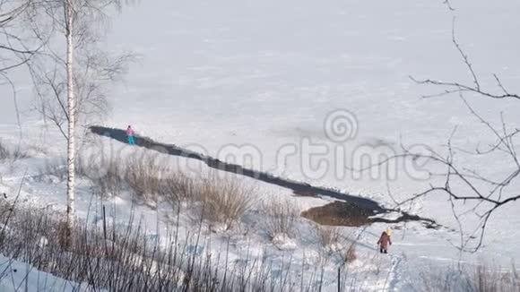 人们沿着冬天公园里一条冰冻的河流的河岸散步视频的预览图