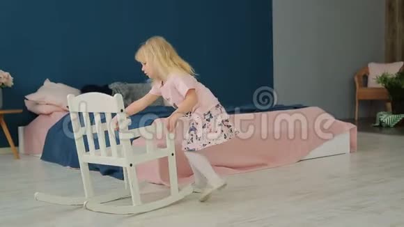 金发小女孩坐在房间里的摇椅上视频的预览图