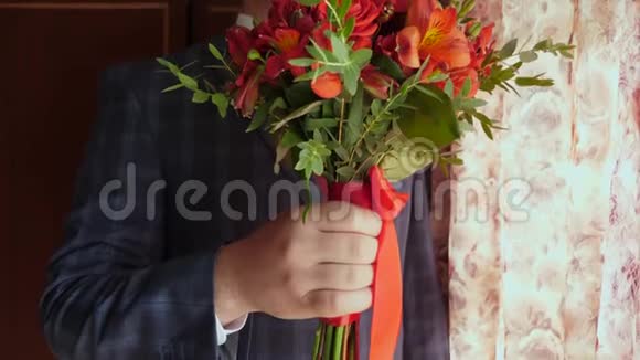 有美丽花朵的商人穿着红色领带和白色夹克的男人手中捧着一束美丽的红玫瑰视频的预览图