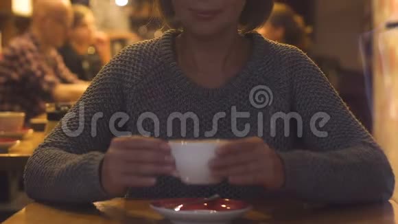 年轻漂亮的女人坐在餐厅喝卡布奇诺热饮料视频的预览图