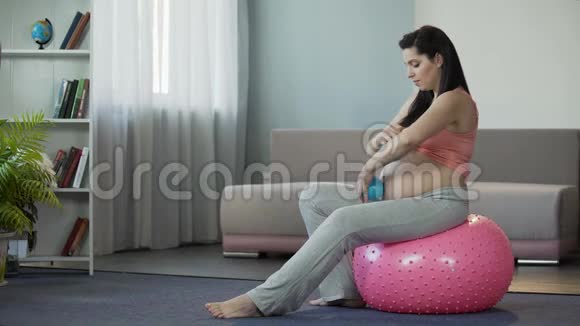 女孩在特殊健身球的帮助下与婴儿一起按摩腹部视频的预览图