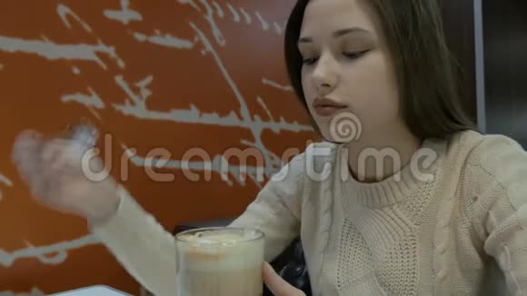 长发美女在咖啡馆里喝一杯用勺子搅拌视频的预览图