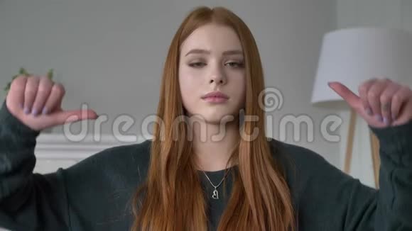 年轻的红发女孩博客作者肖像看着镜头悲伤显示不喜欢的标志家庭舒适的背景视频的预览图