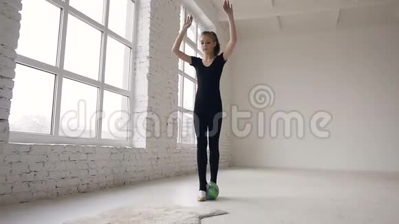 年轻的体操运动员手中拿着球在室内的白色背景下表演杂技动作视频的预览图