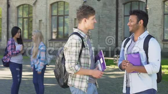 两个微笑的男学生在大学附近谈论毕业晚会视频的预览图