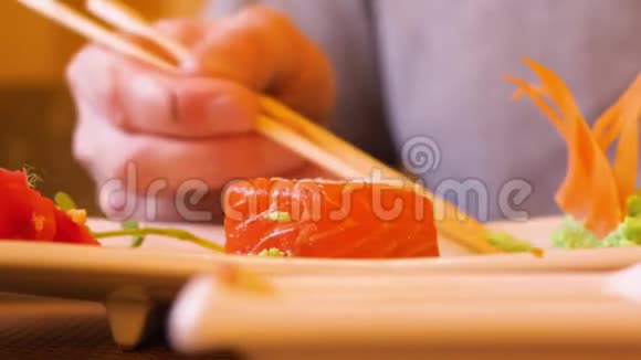 男性手拿着筷子的寿司卷在餐馆里倒酱油视频的预览图
