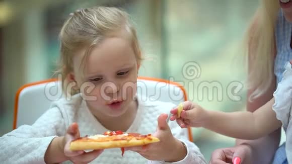 一个小孩子在快餐店吃披萨可爱的小女孩肖像有趣的吃快餐场在商场视频的预览图