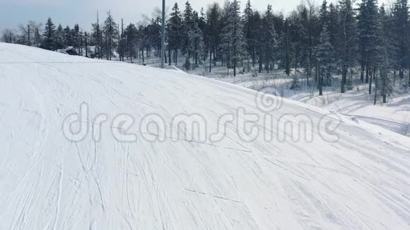 冬季在针叶林附近的跑道上滑雪坡的特写和穿黄色夹克的人滑雪录像滑雪胜地视频的预览图