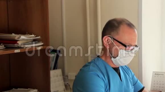 戴眼镜的医生坐在办公室里脱下医用敷料看着摄像机视频的预览图