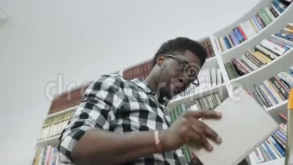 非洲男学生在大学图书馆站在梯子上看书视频的预览图