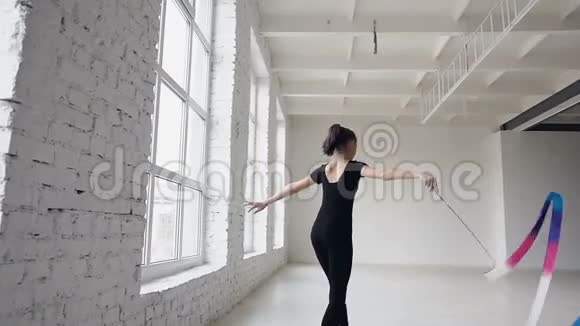 金发可爱的女孩舞蹈艺术体操现代与彩色丝带黑色紧身衣在窗前视频的预览图