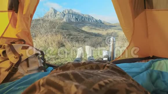 露营的女人躺在帐篷里穿着登山靴在度假时放松从帐篷的角度视频的预览图