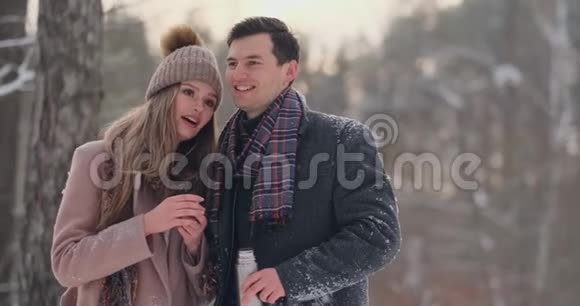 情侣在冬天的森林里喝热水瓶里的茶冬天公园里穿外套的时髦男女视频的预览图