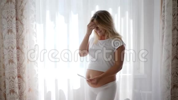 开朗的女性摸大肚子显示超声波扫描未来的宝宝视频的预览图