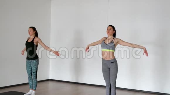 两个女孩在锻炼后做热身运动举手做深呼吸在白色健身房视频的预览图