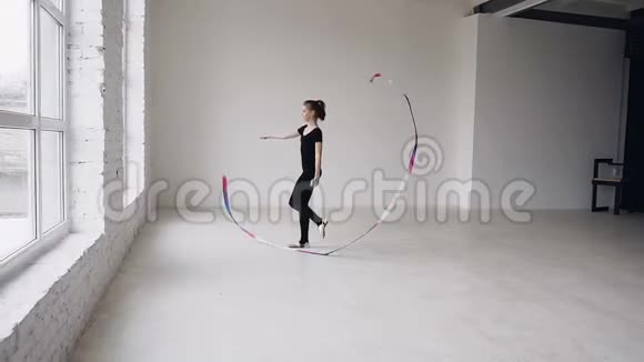漂亮的女子体操运动员在体操学校的白色背景下用丝带跳舞看着相机节奏型视频的预览图