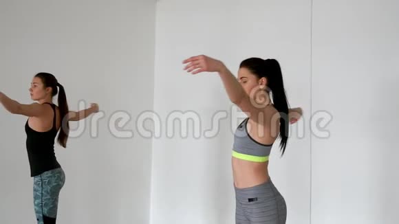 两个在健身房白色背景下参加体育腿的女孩上普拉提课程视频的预览图