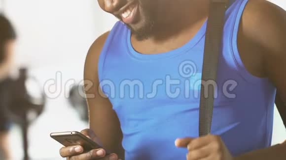 年轻男性站在健身房肩上背着书包在手机上读信息视频的预览图