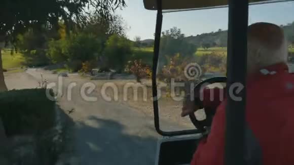 年长的高尔夫球手驾驶高尔夫球车视频的预览图
