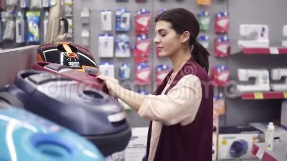 女性消费者在电器商店选择吸尘器接下来是一个展示排把一个垃圾袋从真空里拿出来视频的预览图