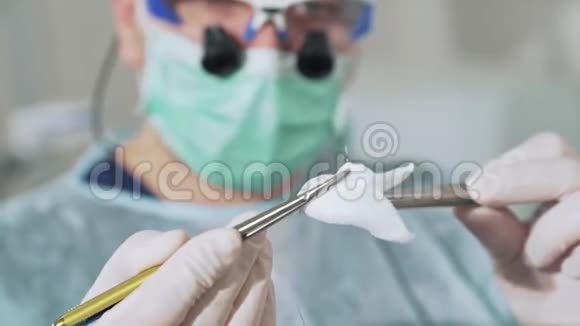 特写镜头外科医生手里拿着一个夹子手里拿着一根手术针背景是一位戴眼镜的医生视频的预览图