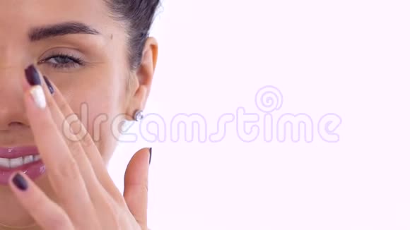 美丽的年轻女人用奶油滋润她的面部皮肤视频的预览图