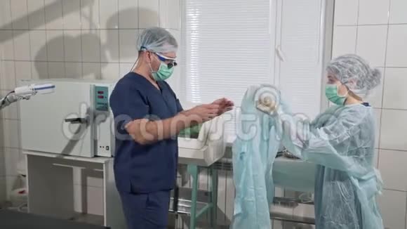 医疗器械健康理念医院女护士帮助医生穿上无菌衣服专业人员视频的预览图