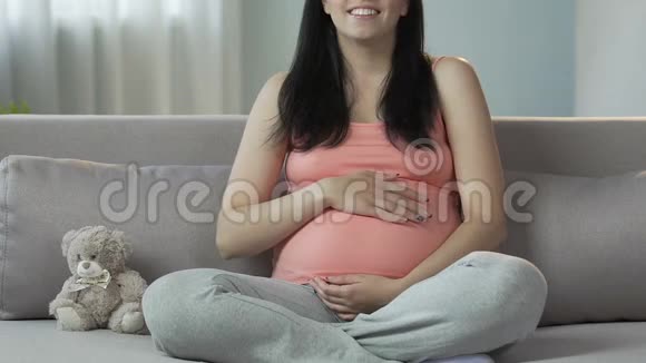 孕妇坐在沙发上揉着肚子微笑着快乐怀孕视频的预览图