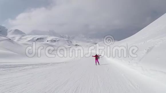 运动滑雪者在冬季的山坡上滑雪并举起双手视频的预览图