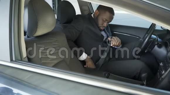 穿着昂贵西装系紧并打开汽车点火装置的美国黑人男子视频的预览图