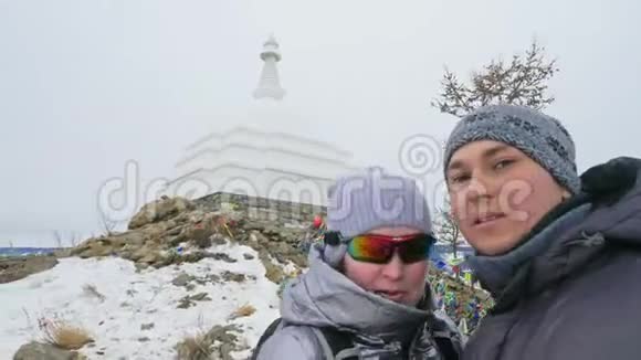 男女在贝加尔湖冰上旅行情侣自拍关闭独特的佛塔伯汗纪念碑标志视频的预览图