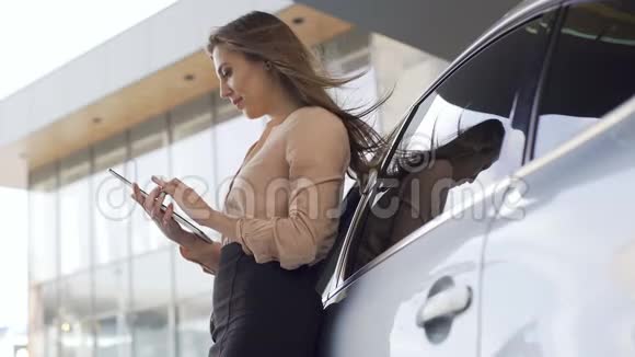 漂亮的销售经理站在汽车附近在平板电脑上工作女商人视频的预览图