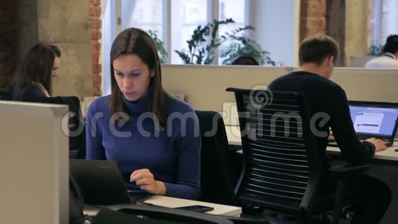 三名员工在现代办公室坐在笔记本电脑前工作视频的预览图