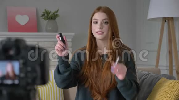 年轻的红发女孩博客写手微笑着对着镜头说话展示新买的东西化妆品口红化妆视频的预览图