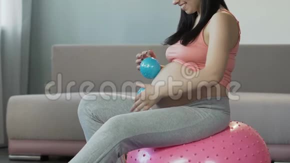 孕妇坐在健身球上腹部滚动按摩球视频的预览图
