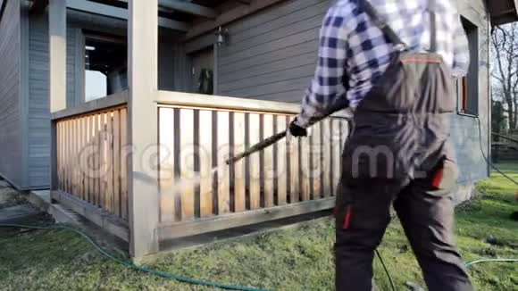 带有动力洗衣机的人清洁露台木制露台栏杆上的高压水清洁器视频的预览图