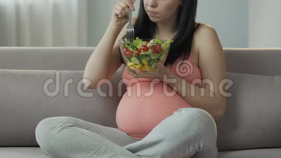 怀孕的女性孩子坐在沙发上吃沙拉保持饮食平衡视频的预览图